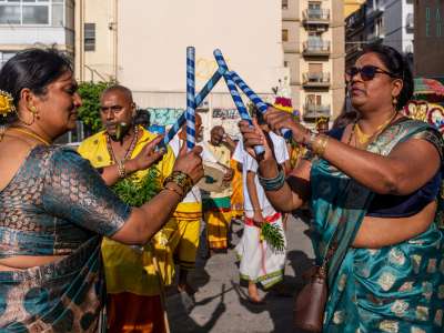 ...e donne percuotono tra di loro alcuni bastoni a strisce blu e azzurre
